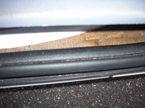 1985 Ford Bronco - A close-up view of the interior door seal and carpet of a vehicle.