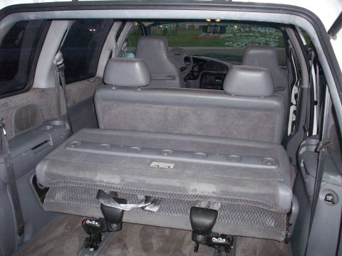 1985 Ford Bronco - The interior of a minivan shows a folded rear seat and gray upholstery.