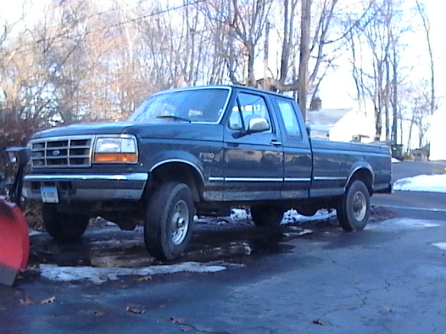 Dark blue 1990s Ford F-250 pickup truck with plow