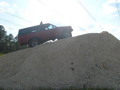 red SUV on a dirt pile, trees and power lines in background
