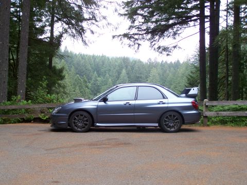 1998 Subaru Legacy - A gray Subaru Impreza WRX STI is parked on a gravel lot with a forest in the background.