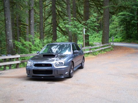 1998 Subaru Legacy - A gray Subaru Impreza WRX STI is parked on a gravel lot surrounded by a forest.