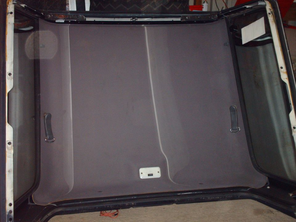 Car interior headliner with grab handles and a light fixture