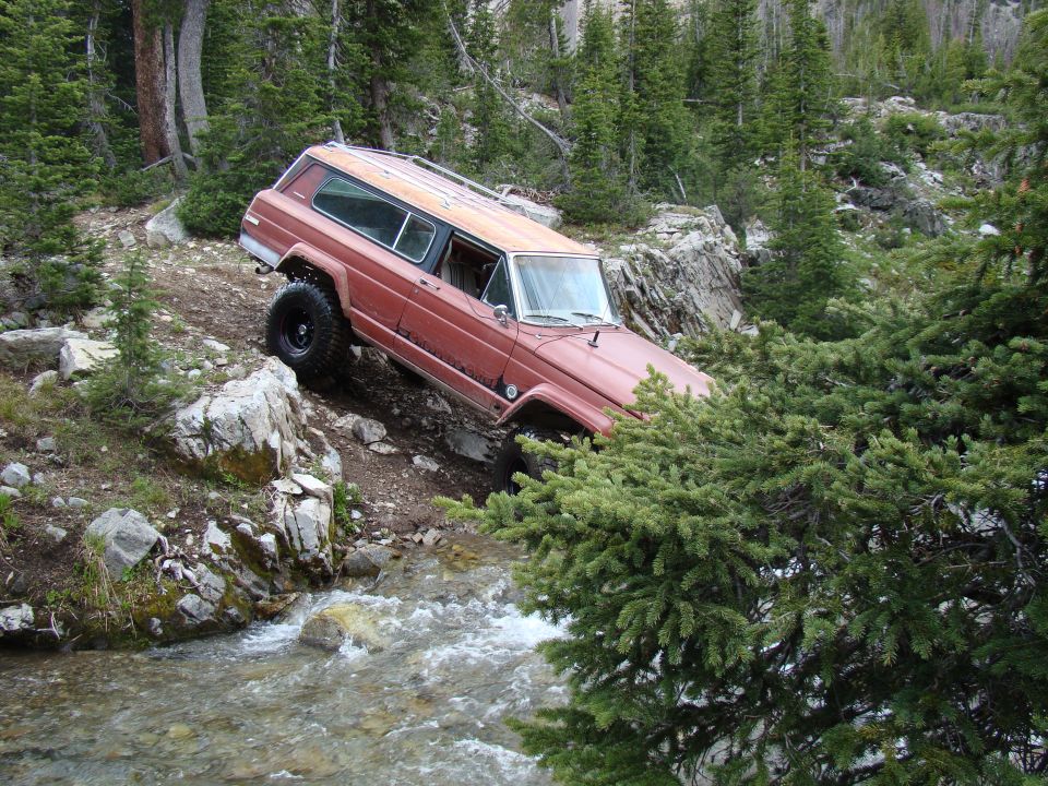 Red Jeep Cherokee Chief off-roading on a rocky stream bed
