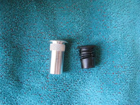 2003 Mercury Marauder - Two automotive door parts, a silver pin and a black bezel, are shown on a textured blue surface.