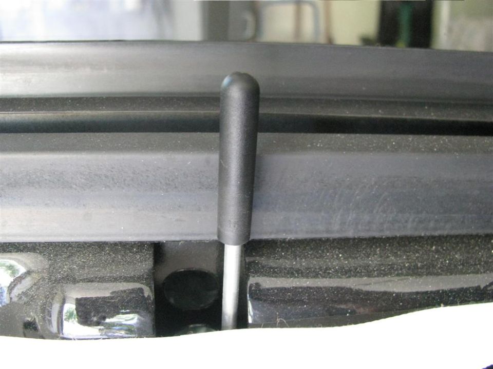 Close-up of a black hood latch lever extending from a black surface