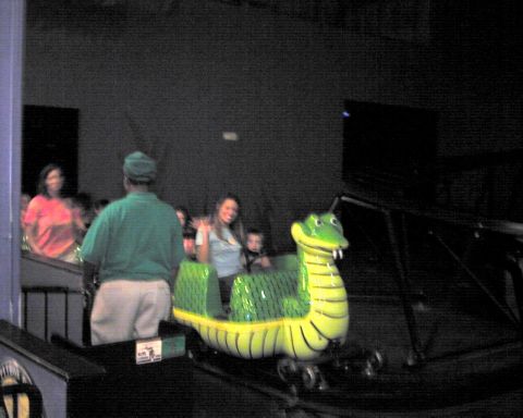 1990 Ford Taurus - A whimsical alligator-themed roller coaster car carries passengers through an amusement park attraction.