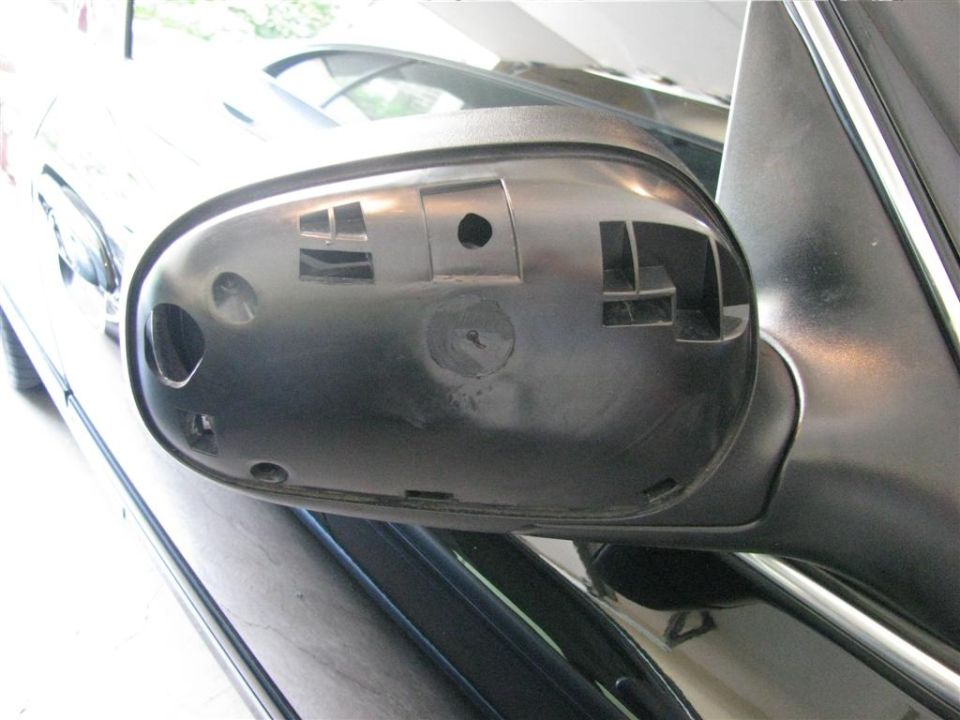 Black plastic housing for a car side mirror, showing mounting points and cutouts