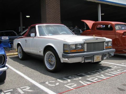 2003 Mercury Marauder - A white convertible with a maroon roof and wire wheels is parked at a car show.