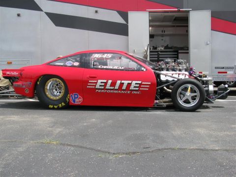 2003 Mercury Marauder - A red drag car with its engine exposed is parked next to a trailer at a car show.