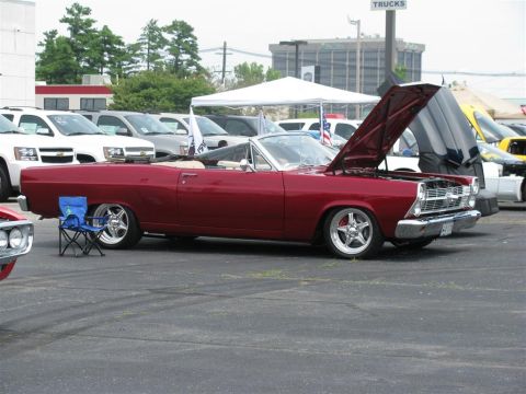 2003 Mercury Marauder - A red convertible with its hood open is displayed at a car show, with other vehicles and tents in the background.