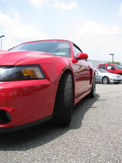 2003 Mercury Marauder - A red convertible sports car is parked at an outdoor event with other vehicles in the background.