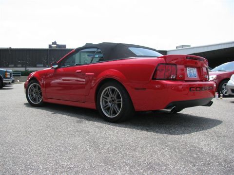 2003 Mercury Marauder - Red convertible Mustang Cobra seen from the rear, a black top and a prominent spoiler. Another red car is visible in the background.