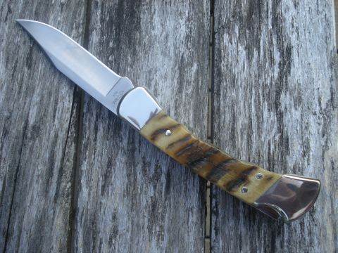 2000 Ford Crown Victoria - A close-up view of a folding knife with a polished blade and a distinctive striped handle, set against a rustic wooden background.