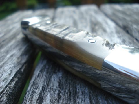 2000 Ford Crown Victoria - A knife handle, wood grain and polished metal, rests on a weathered wooden table.
