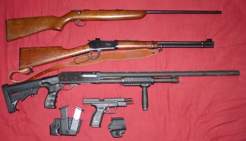 2006 Ford E350 - A variety of firearms, including rifles and a handgun, are displayed on a red surface.