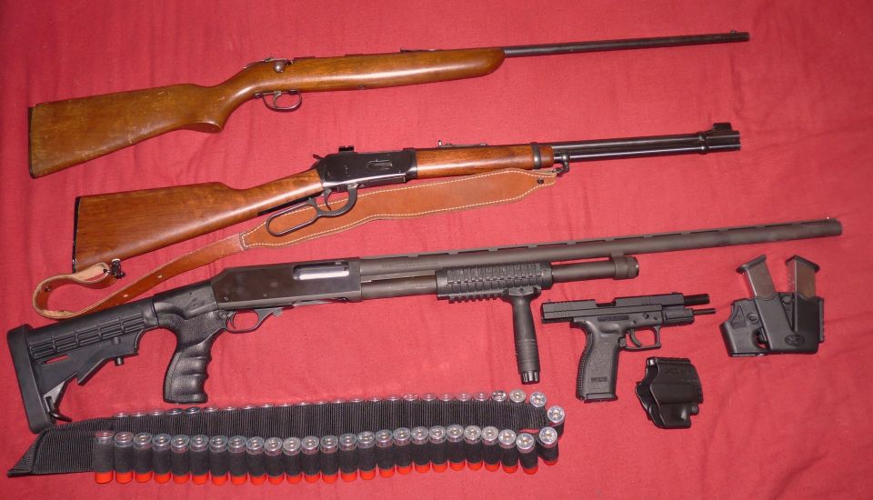 Three firearms and ammunition laid out on a red surface