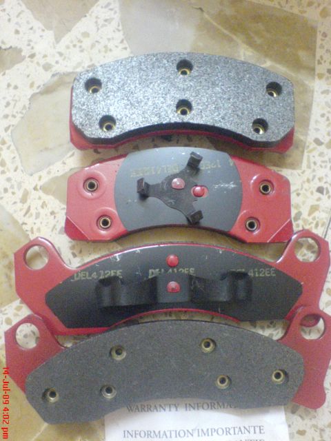 1992 Ford Crown Victoria - Stack of four brake pads, some with part numbers visible, on a patterned surface.