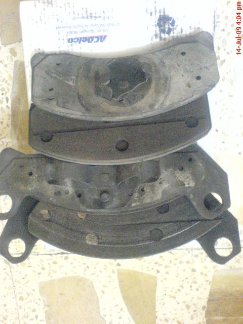 1992 Ford Crown Victoria - Four used brake pads are stacked on top of each other, with partial ACDelco packaging in the background.