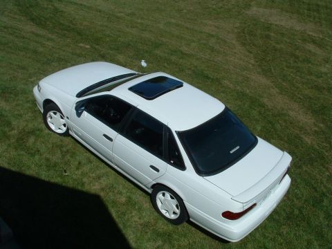 1993 Ford Taurus - A white sedan with a sunroof sits on a grassy lawn, viewed from a high angle.