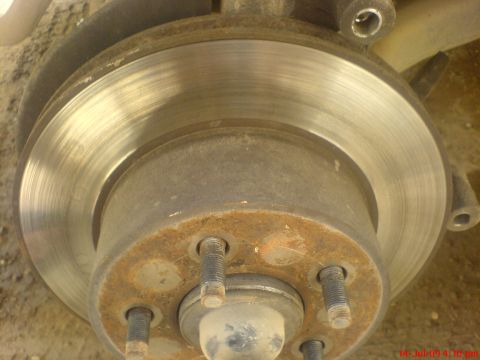 1992 Ford Crown Victoria - A close-up view of a brake rotor and hub assembly, showing signs of rust and wear on the metal components.