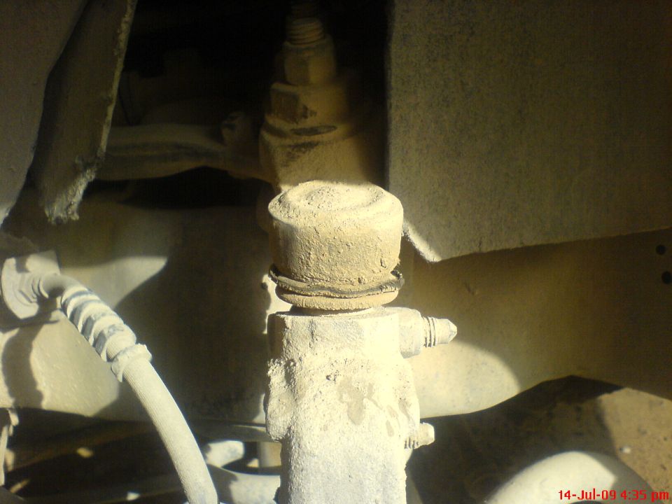 Dust-covered upper ball joint and boot on a front spindle with grease zerk and brake hose