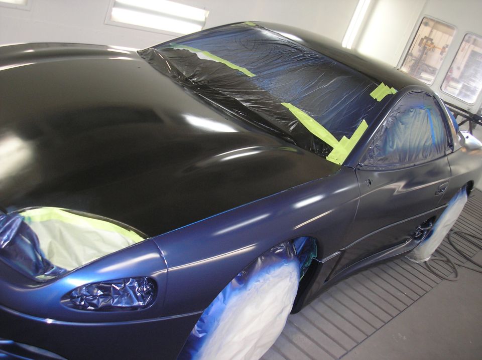 Car bodywork masked with plastic and tape, ready for painting