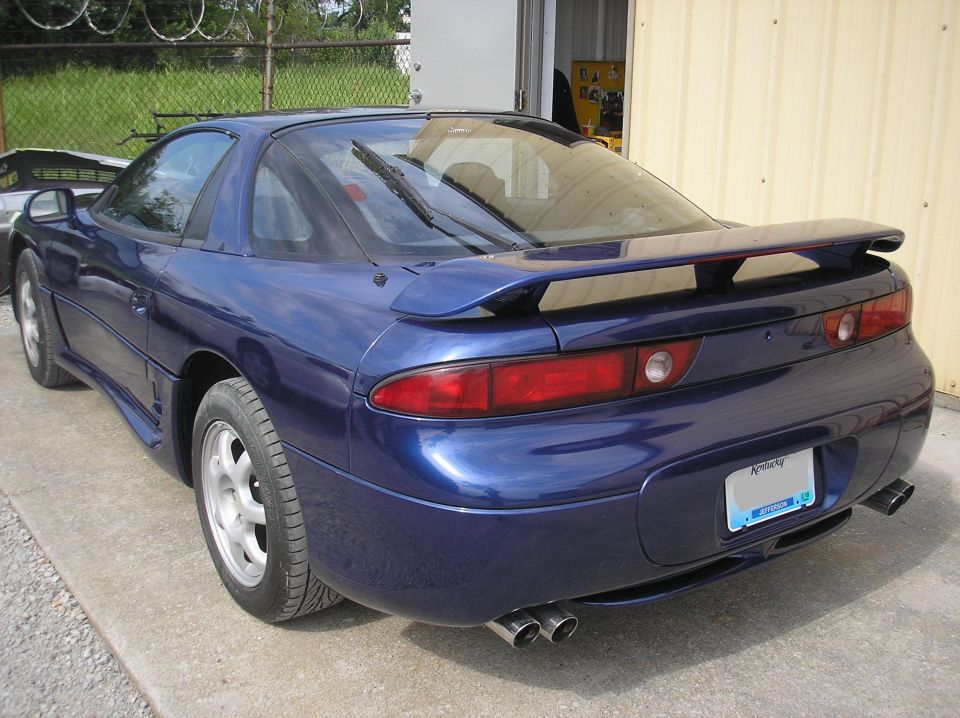 Blue sports car rear 3/4 view with spoiler and dual exhaust pipes