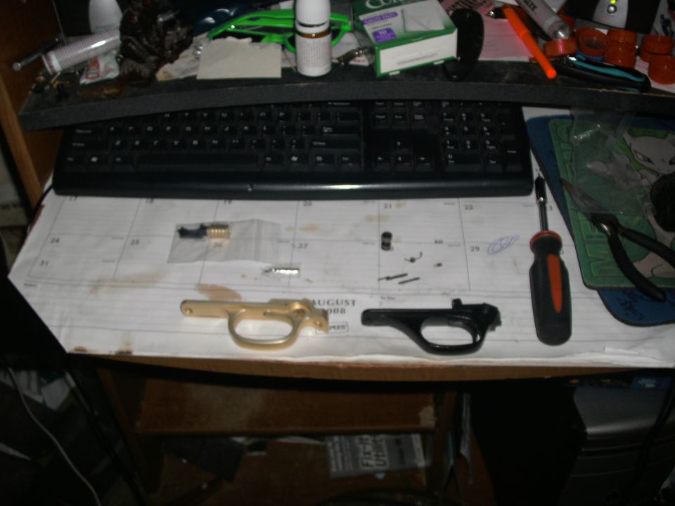 Gun trigger assemblies and small parts laid out on an August calendar page