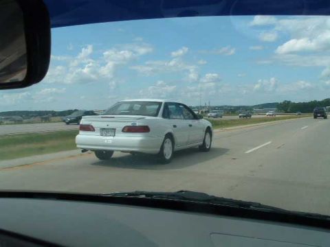 1993 Ford Taurus - White 1993 Ford Taurus seen from inside another vehicle on a highway.