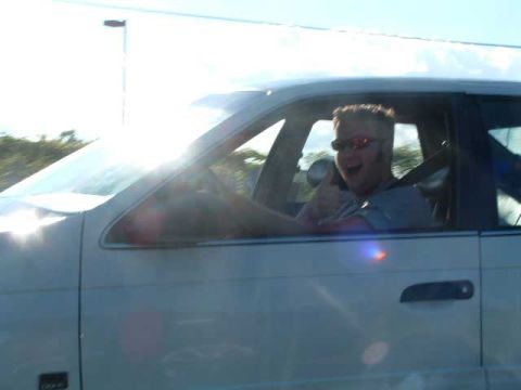 1993 Ford Taurus - A man in a white 1993 Ford Taurus gives a thumbs up while driving.
