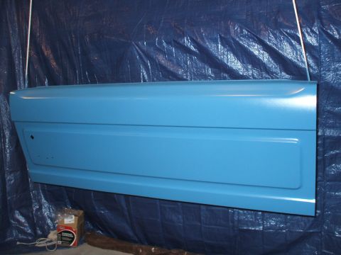 1990 Ford Bronco - A single car door, painted blue, is suspended in front of a dark tarp.