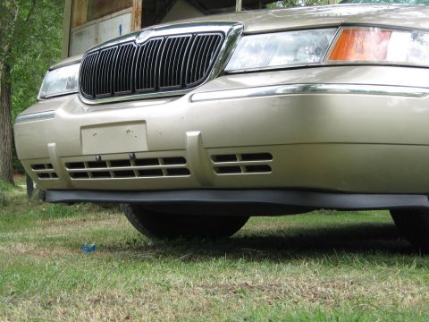 2000 Mercury Grand Marquis - Front view of a gold 2000 Mercury Grand Marquis, highlighting its distinctive grille and bumper design.