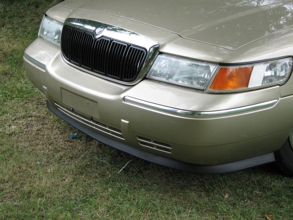 Front end of a gold 2000 Mercury Grand Marquis with a black grille and chrome trim