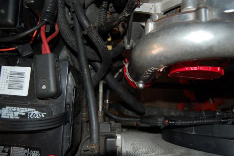 1985 Mercury Grand Marquis - A close-up view of various engine components, including a battery and intake piping, is shown.