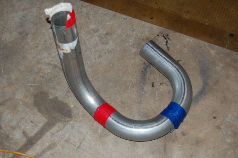 1985 Mercury Grand Marquis - A section of bent metal pipe, possibly for an exhaust system, is marked with colored tape.