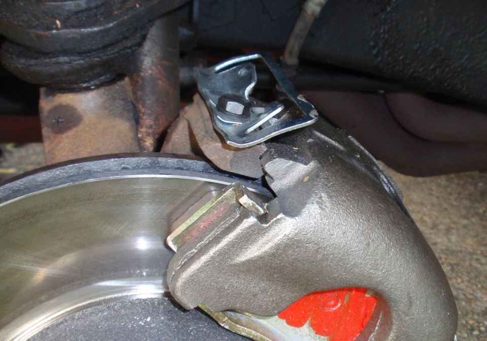 Brake caliper and rotor with red brake pad visible