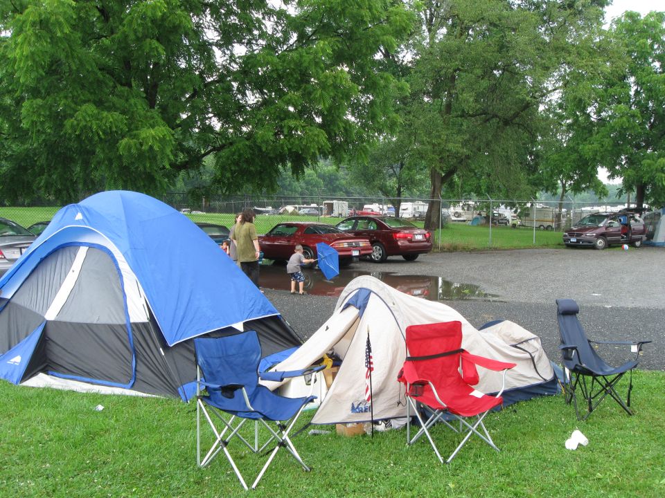 Red coupe with pop-up headlights parked at campsite