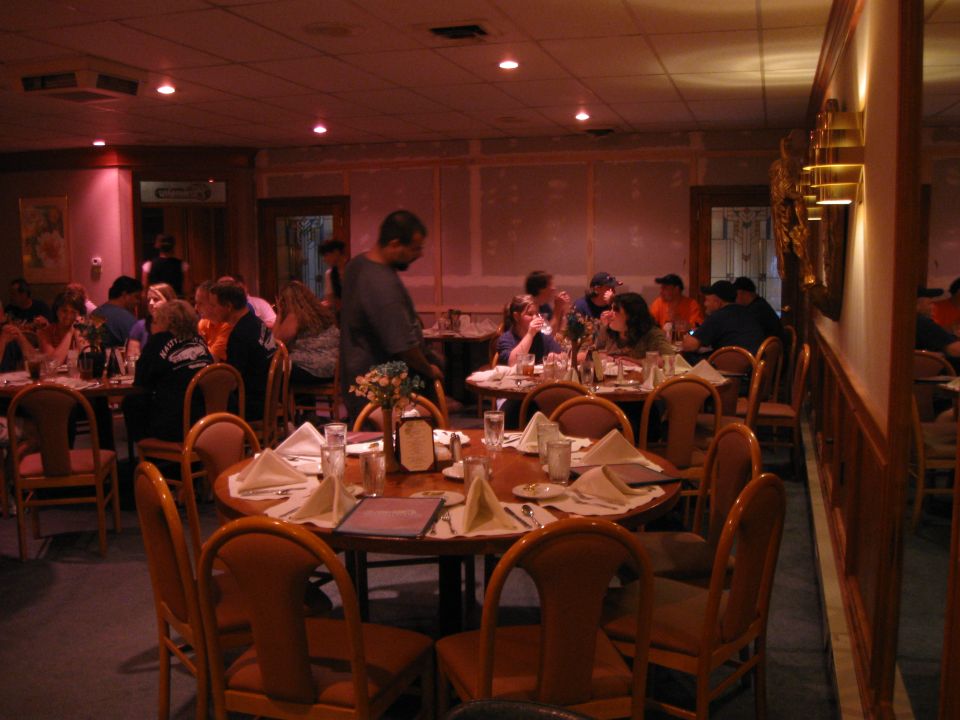 Restaurant dining room with tables set for dinner, people seated at tables, and a man standing near a table