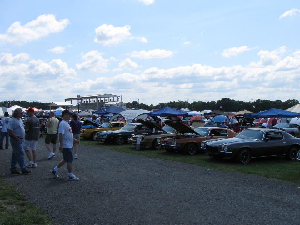 Cars parked in a row with hoods up at an outdoor event