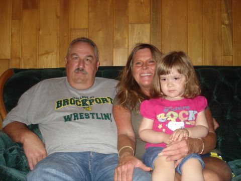 2000 Ford Crown Victoria - A man, woman, and young child pose for a photo while seated on a couch.