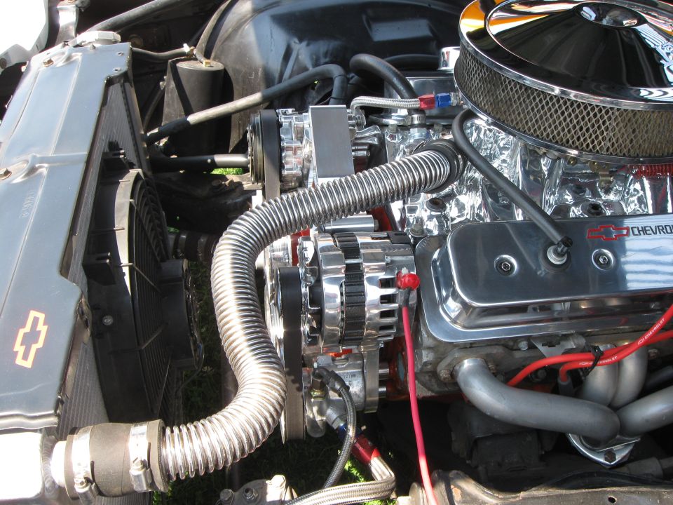 Close-up of a chrome V8 engine, showing air filter, alternator, and exhaust manifold