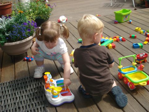 2000 Ford Crown Victoria - Children enjoy playtime on a sunny day, surrounded by toys and greenery on a wooden deck.