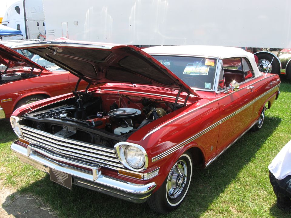 Red convertible with hood open, showing engine and chrome grille