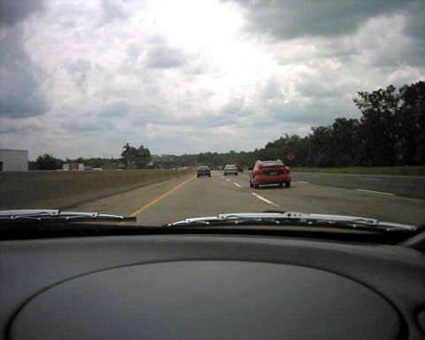 1990 Ford Taurus - Driving on a highway with multiple cars on the road under a cloudy sky.