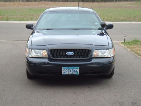 2000 Ford Crown Victoria - The front of a dark blue Ford Crown Victoria is visible, a black grille with the Ford logo and a Minnesota license plate.