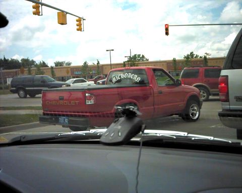 1990 Ford Taurus - A red Chevrolet S-10 pickup truck is seen from behind in traffic, with a sticker on the rear window.