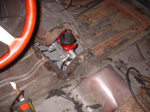 1970 Ford Torino - Interior view of a car's transmission tunnel and floor, with a wooden steering wheel visible.