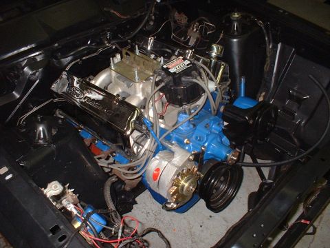 1970 Ford Torino - The engine bay of a 1970 Ford Torino shows a blue V8 engine with chrome valve covers and various components.