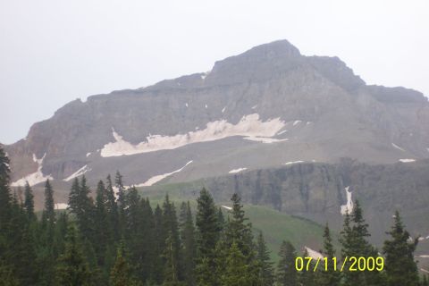 1996 Ford Bronco - A scenic mountain vista with snow-capped peaks and evergreen trees, a website watermark.